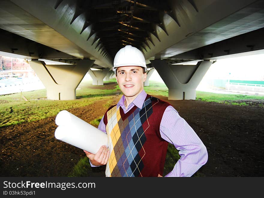 Industrial theme: architect, on a workplace, in a warm winter jacket and a helmet, has control over a tablet. Industrial theme: architect, on a workplace, in a warm winter jacket and a helmet, has control over a tablet.