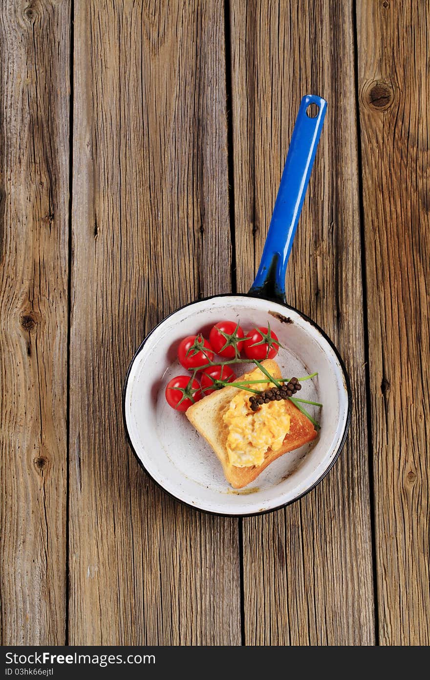 Scrambled eggs on toast and tomatoes in a pan