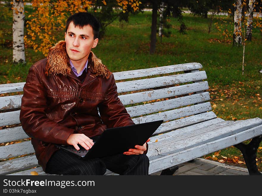 Man with laptop outdoor, in the autumn park. Man with laptop outdoor, in the autumn park.