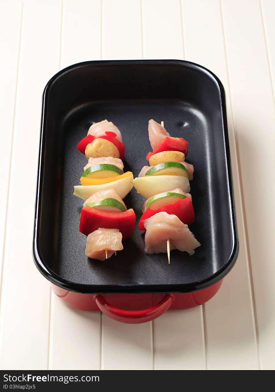 Raw chicken shish kebabs in a roasting pan