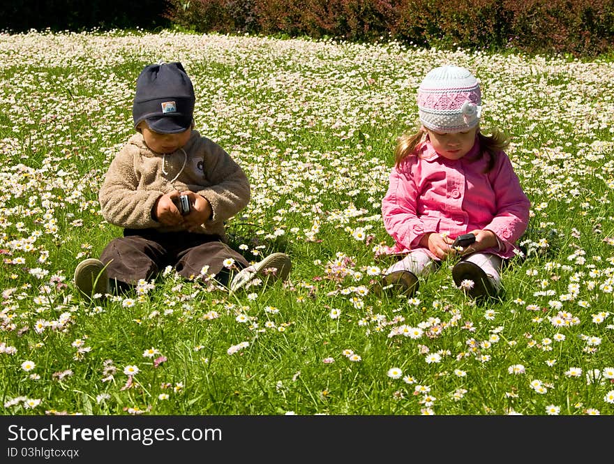 Boy and girl playing in the park with mobile phones