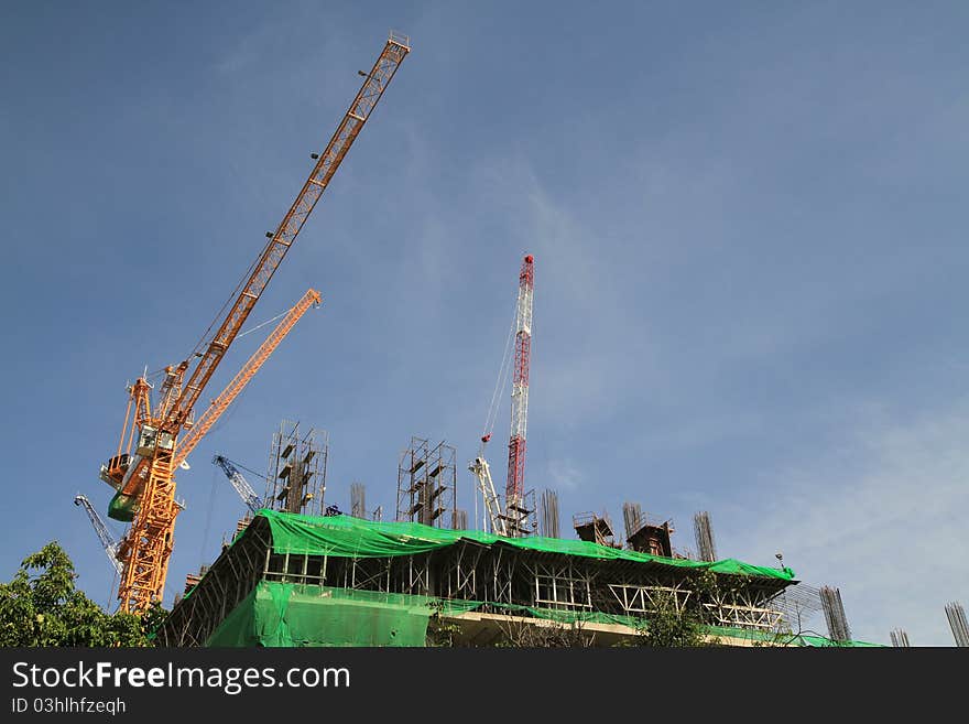 Crane and building construction on blue sky background.