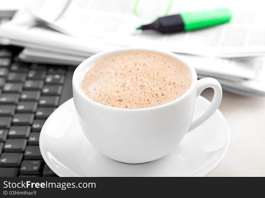 Cappuccino cup with laptop and newspaper