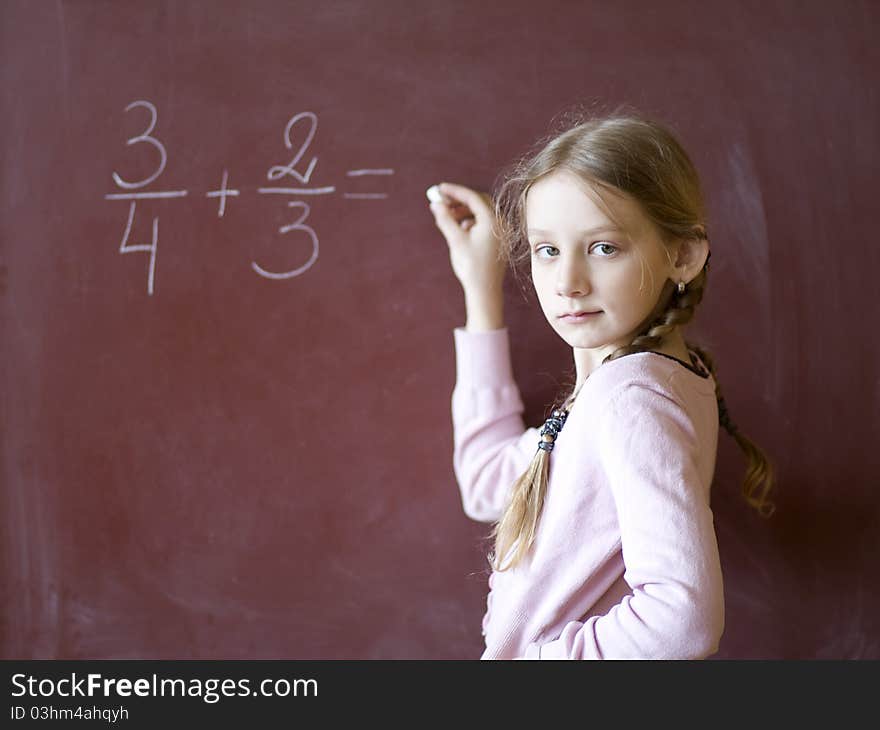 Young schoolgirl standing by the blackboard