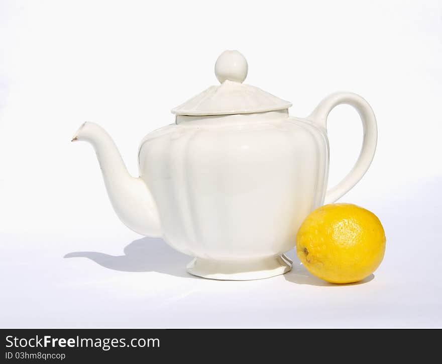 Still-life with white teapot and lemon on white background