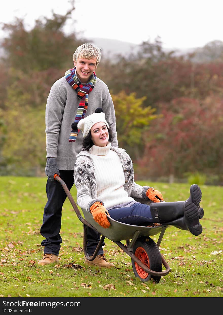 Young couple playing in wheelbarrow smiling at camera