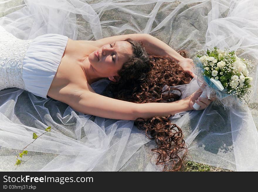 The bride with a bouquet lying on a grass. The bride with a bouquet lying on a grass