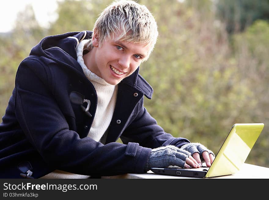 Young man with laptop computer smiling at camera