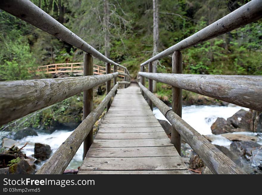 Wooden bridge across mountain river, Austrian Alps