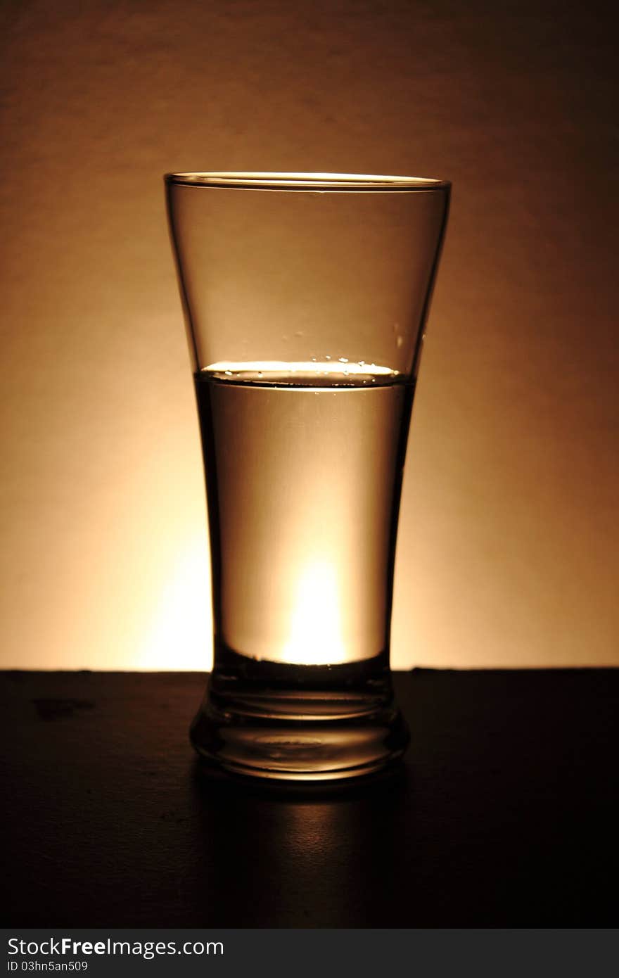 Water in a glass isolated on a gold background. Water in a glass isolated on a gold background.