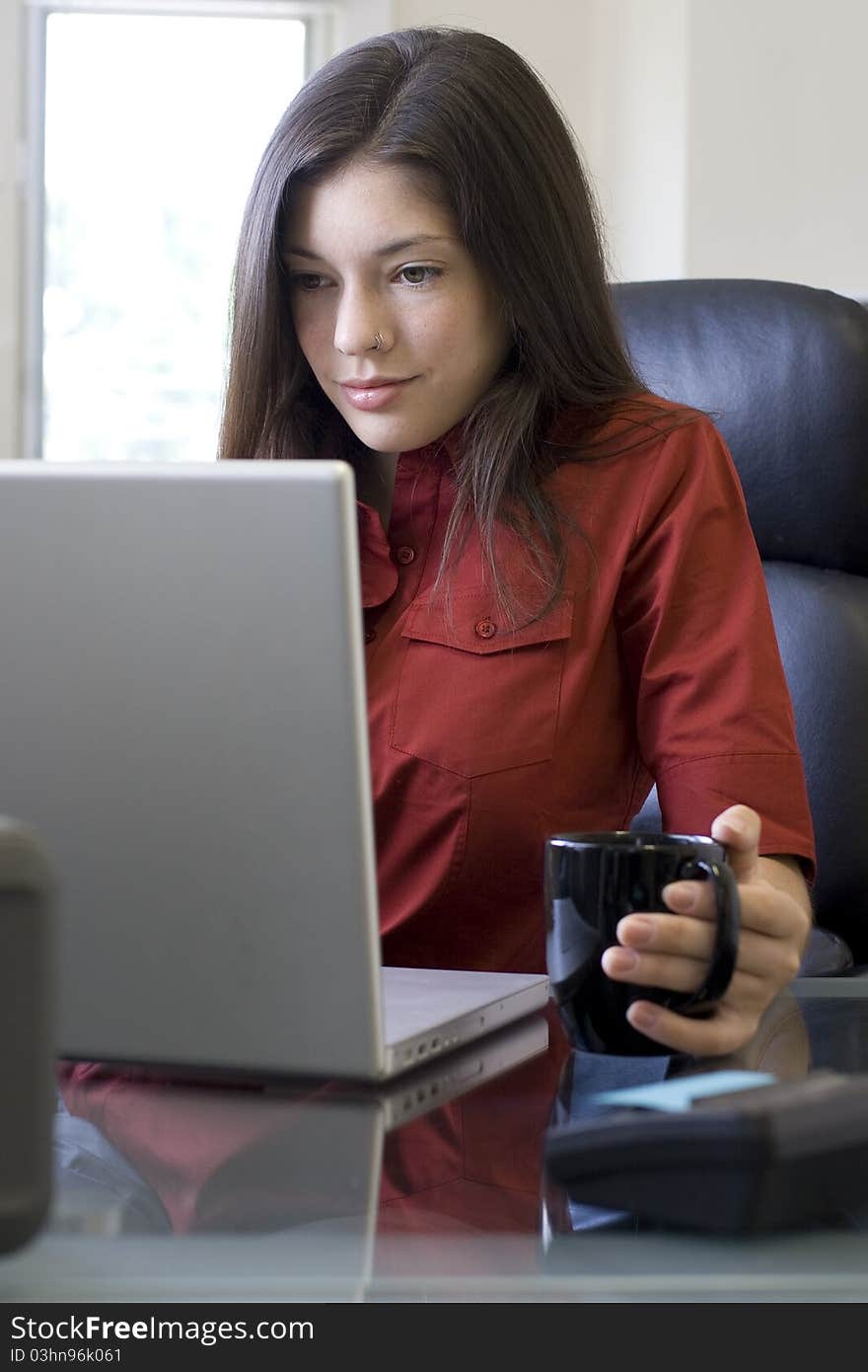 Young businesswoman with laptop surfing the web at her desk