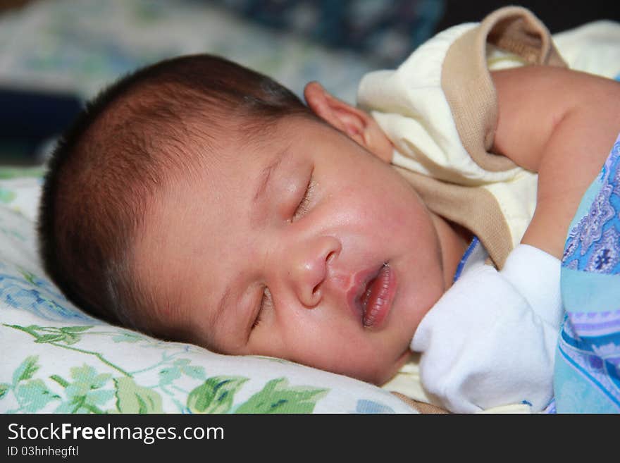 A newborn baby boy is sleeping deeply in his mother's arm. A newborn baby boy is sleeping deeply in his mother's arm.