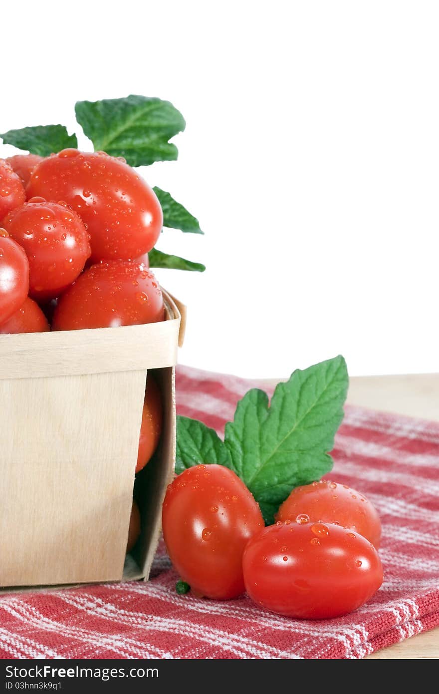 Fresh ripe grape tomatoes with leaves in wood basket. A grape tomato is a class of tomatoes believed to be of southeast Asian origin, shaped similarly to the oblong plum tomatoes but having the small size and sweetness of cherry tomatoes. Grape tomatoes produce small and typically oblong fruits. Introduced to the worldwide market in the 1990s, they have gained substantial popularity, due at least in part to their higher sugar content compared to regular tomatoes, and due to their smaller, bite-sized shape. Fresh ripe grape tomatoes with leaves in wood basket. A grape tomato is a class of tomatoes believed to be of southeast Asian origin, shaped similarly to the oblong plum tomatoes but having the small size and sweetness of cherry tomatoes. Grape tomatoes produce small and typically oblong fruits. Introduced to the worldwide market in the 1990s, they have gained substantial popularity, due at least in part to their higher sugar content compared to regular tomatoes, and due to their smaller, bite-sized shape