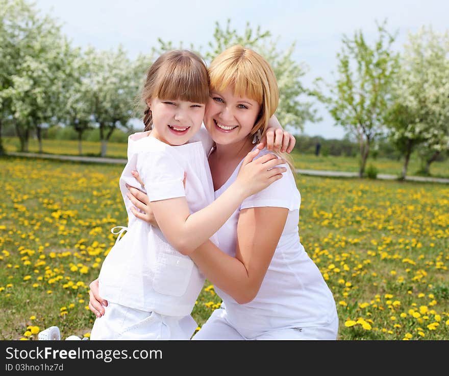 Happy girl and her mother in the spring park among flowers. Happy girl and her mother in the spring park among flowers