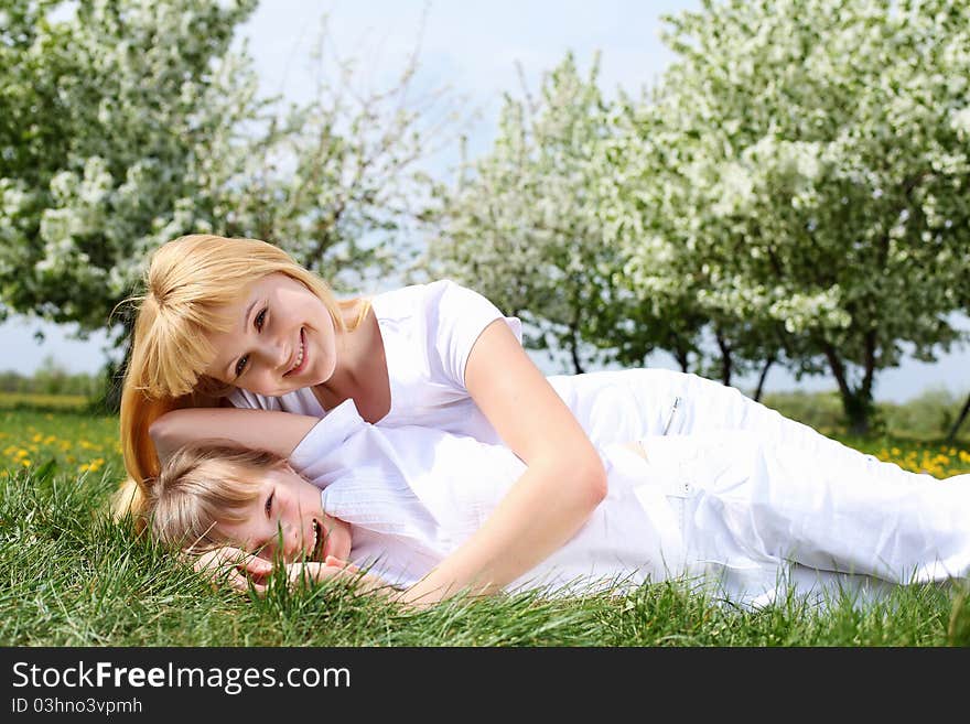 Happy girl and her mother in the spring park among flowers. Happy girl and her mother in the spring park among flowers