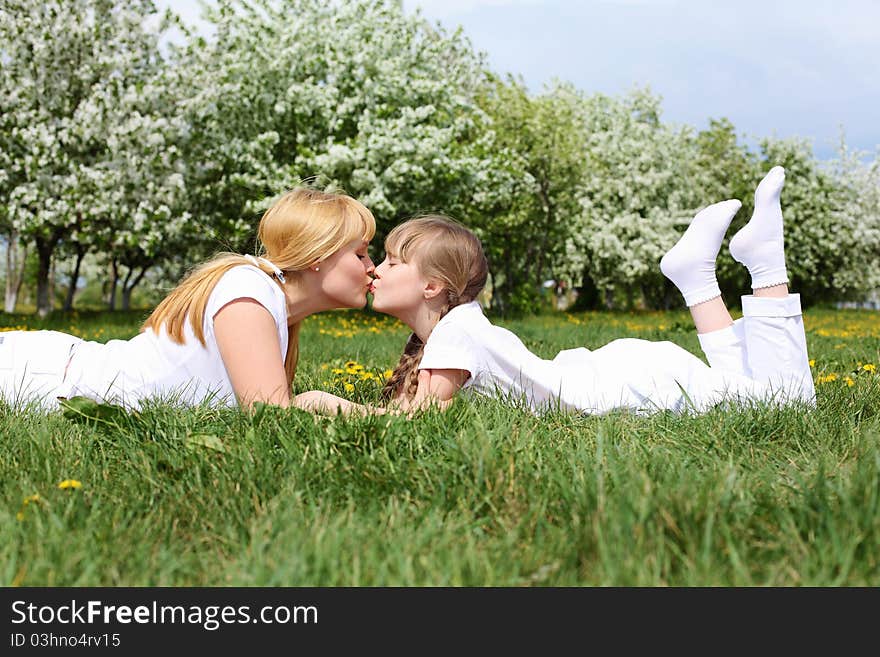 Happy girl and her mother in the spring park among flowers. Happy girl and her mother in the spring park among flowers