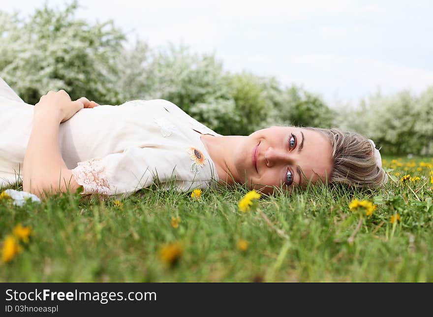 Young woman in spring park among flowers