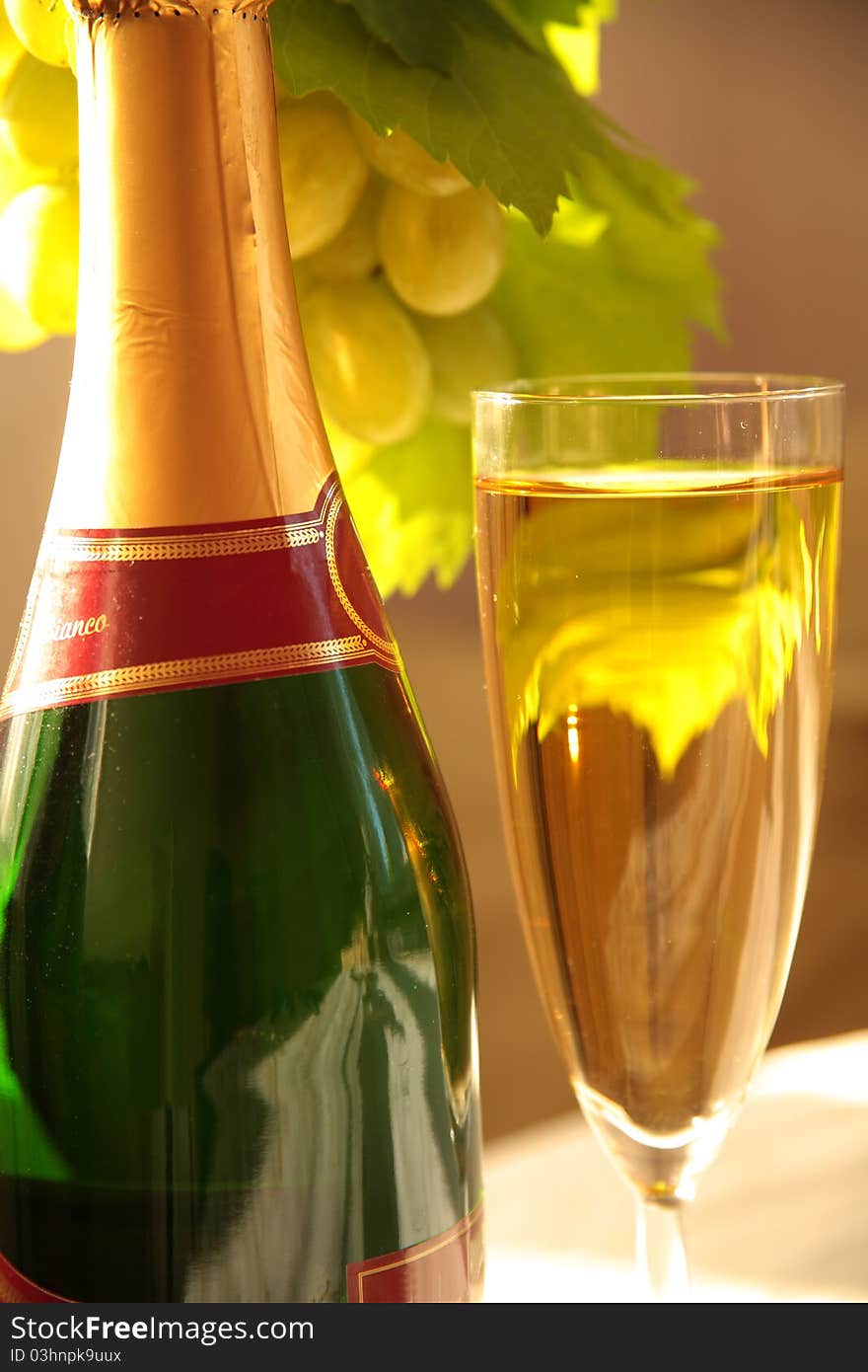 Close-up of bottle of champagne and glass. On backrground blured grape-vine with grapes. Close-up of bottle of champagne and glass. On backrground blured grape-vine with grapes.