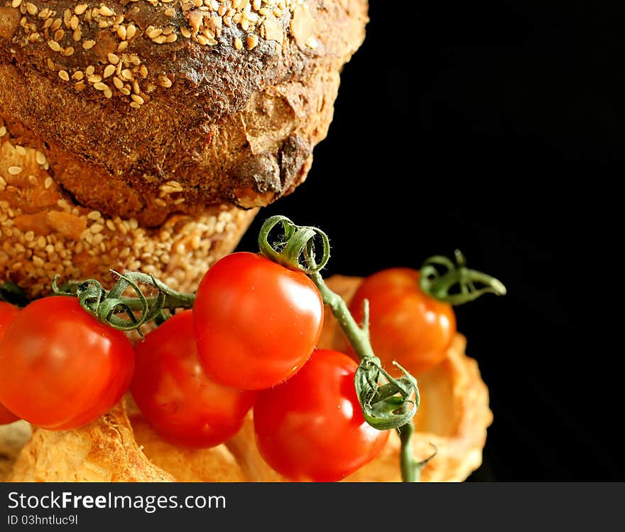 Tomatoes and bread on black background