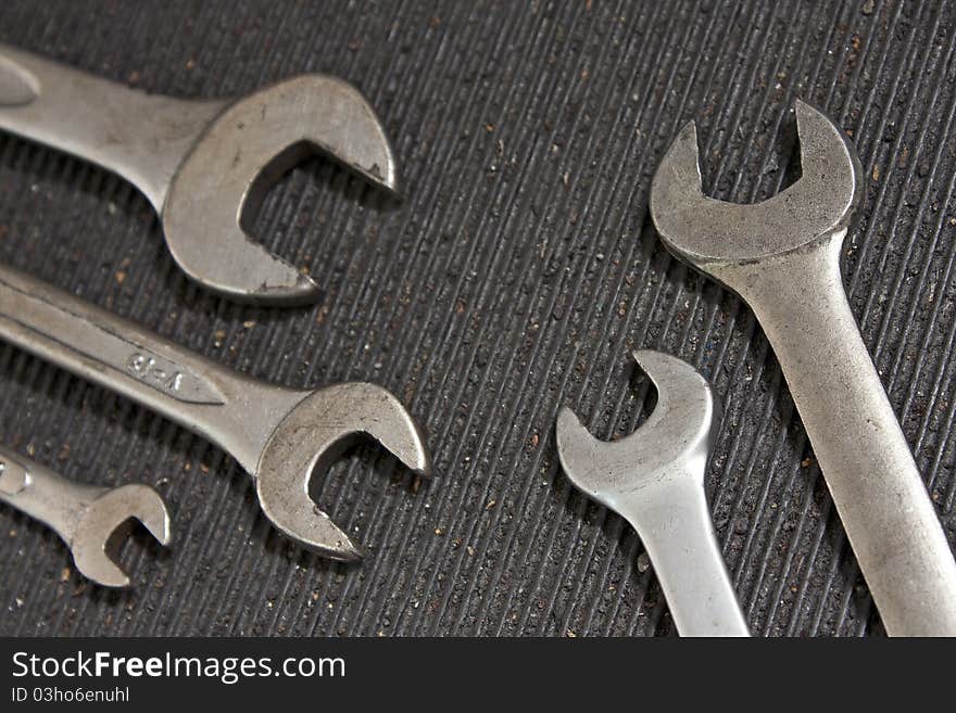 Set of used wrenches in a dirty black rubber mat