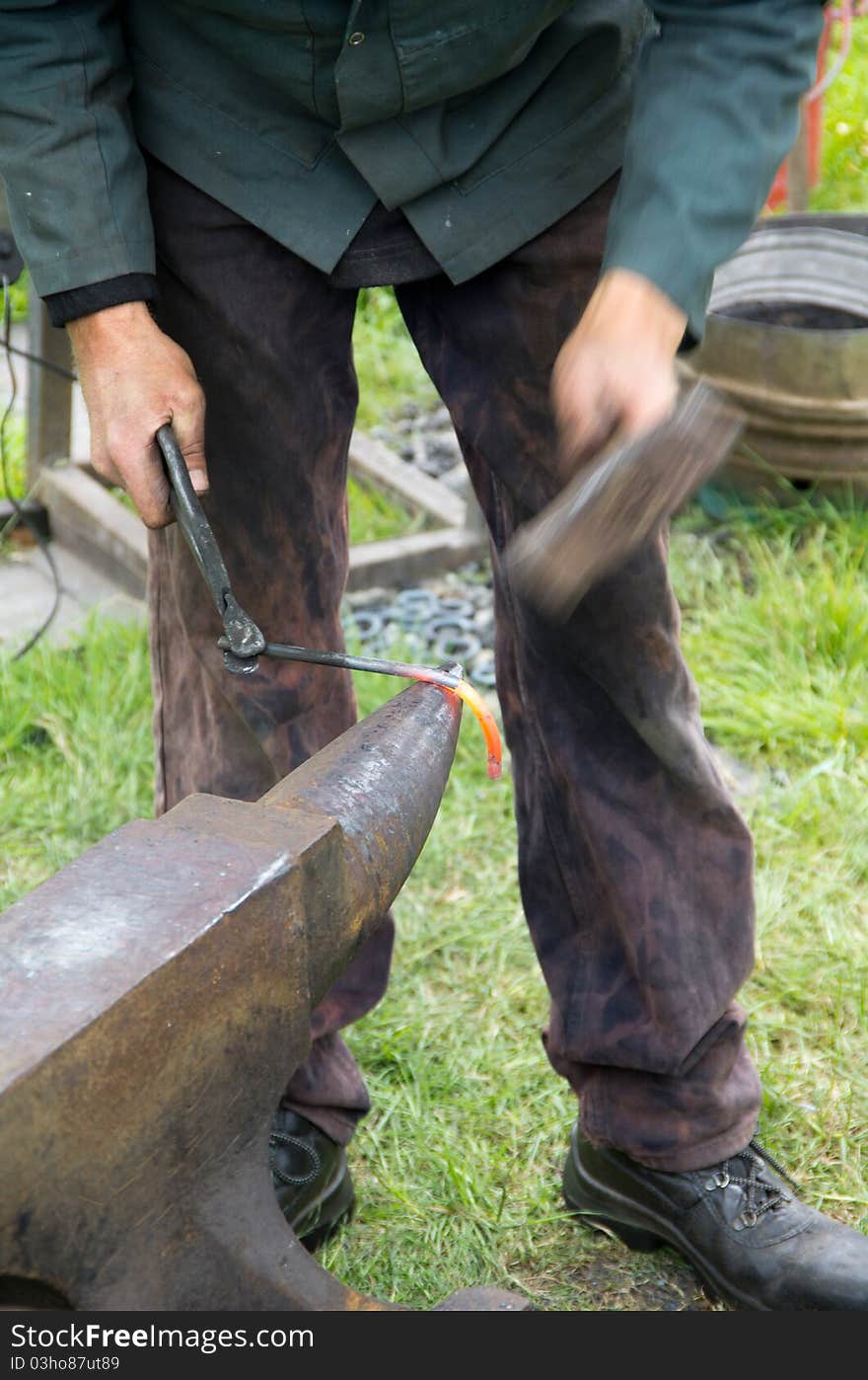 A blacksmith hammers red hot iron with intentional motion blur. A blacksmith hammers red hot iron with intentional motion blur