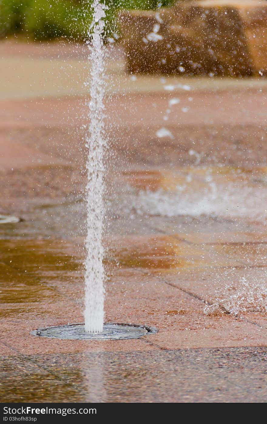 A Water Fountain Jet Spraying Water Up on a Patterned Floor. A Water Fountain Jet Spraying Water Up on a Patterned Floor