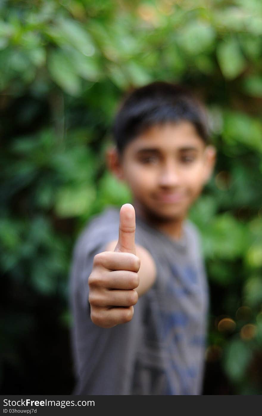 An handsome indian kid showing thumbs up for success