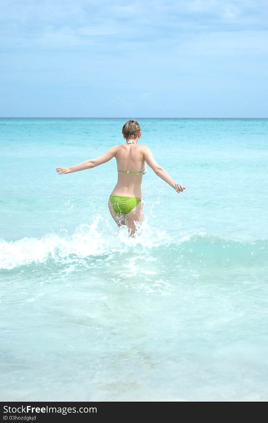 Young woman running into the ocean