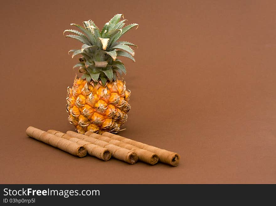 Baby pineapple and sweets on brown background. Baby pineapple and sweets on brown background