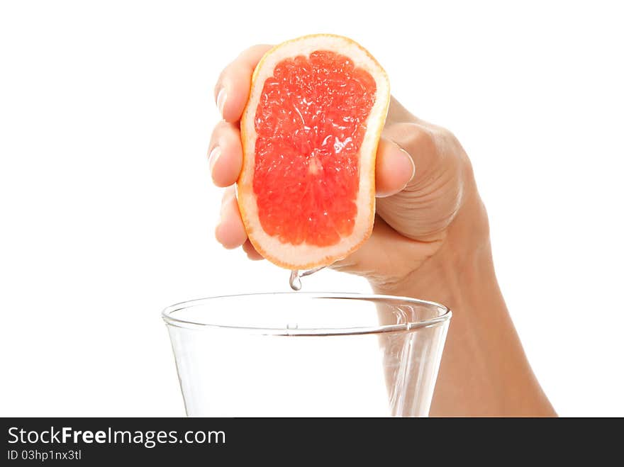 Hand squeezing red orange or grapefruit juice in glass isolated on a white background