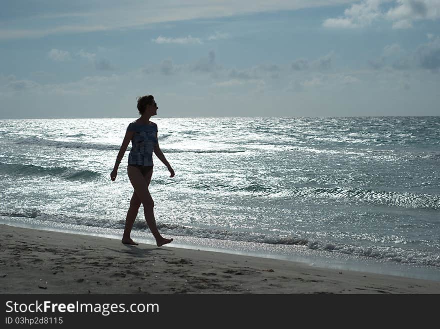 Woman silhouette on the beach walking