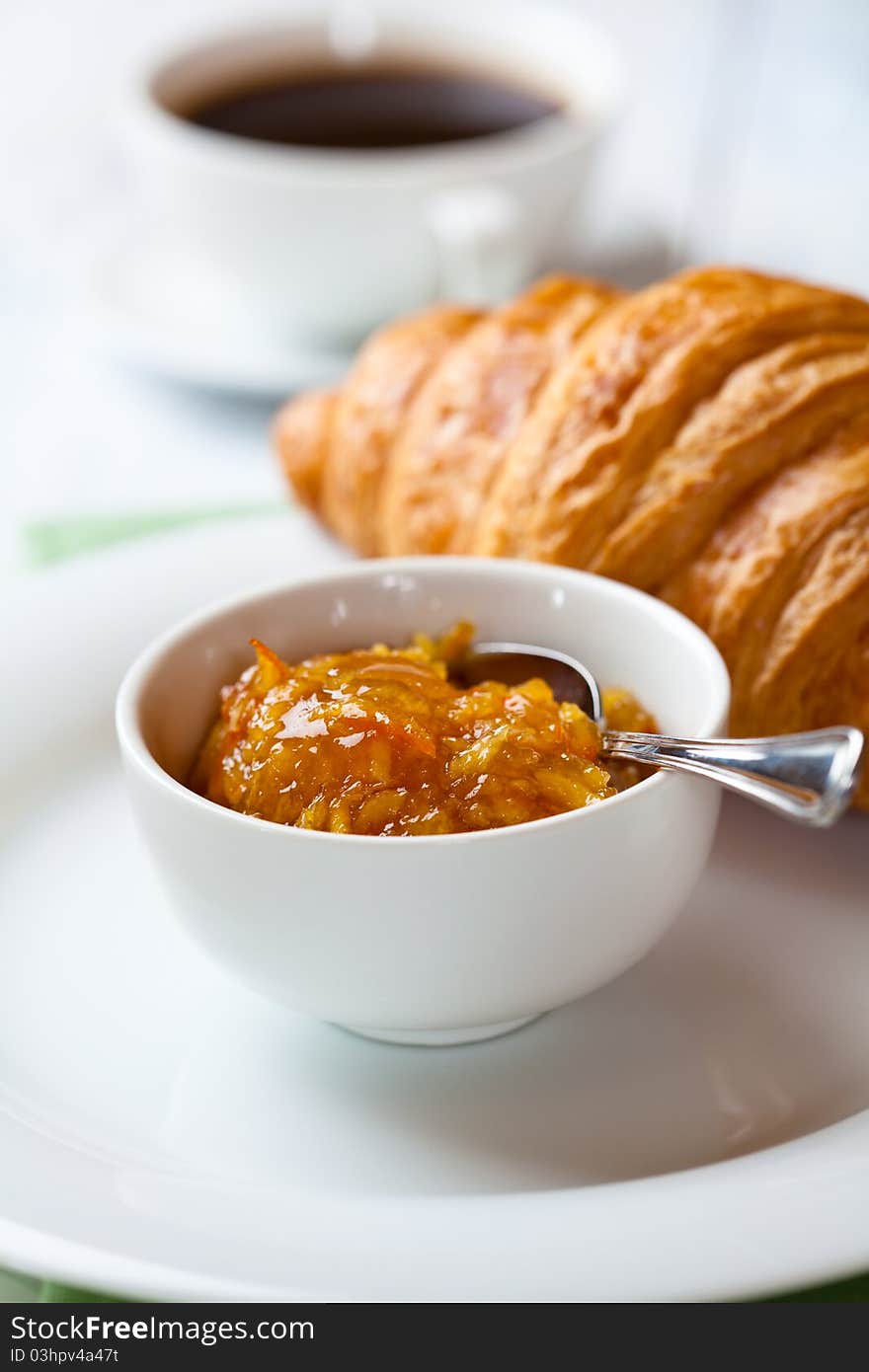 Closeup of orange jam and croissant