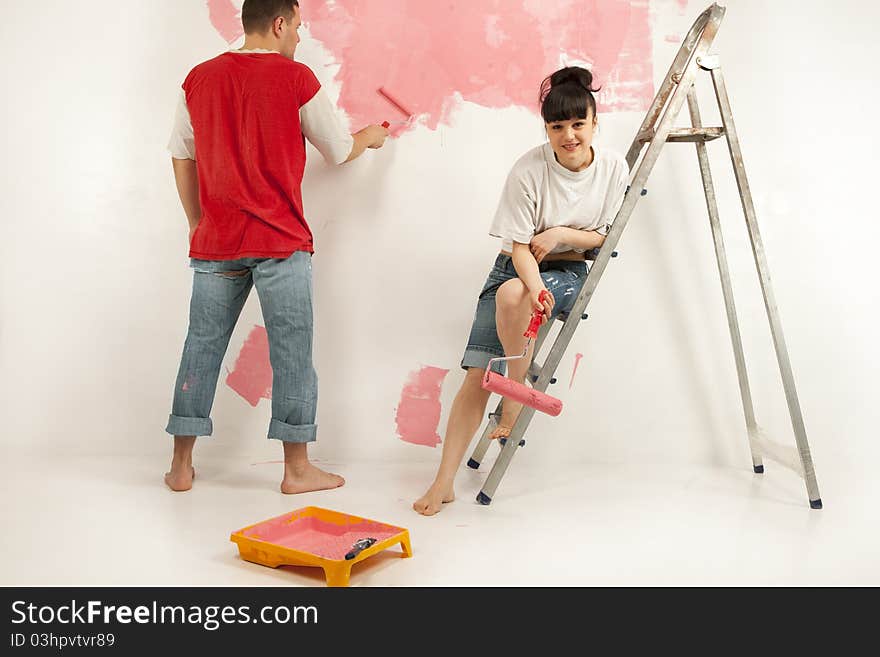 Cheerful young couple of workers preparing to painting a wall