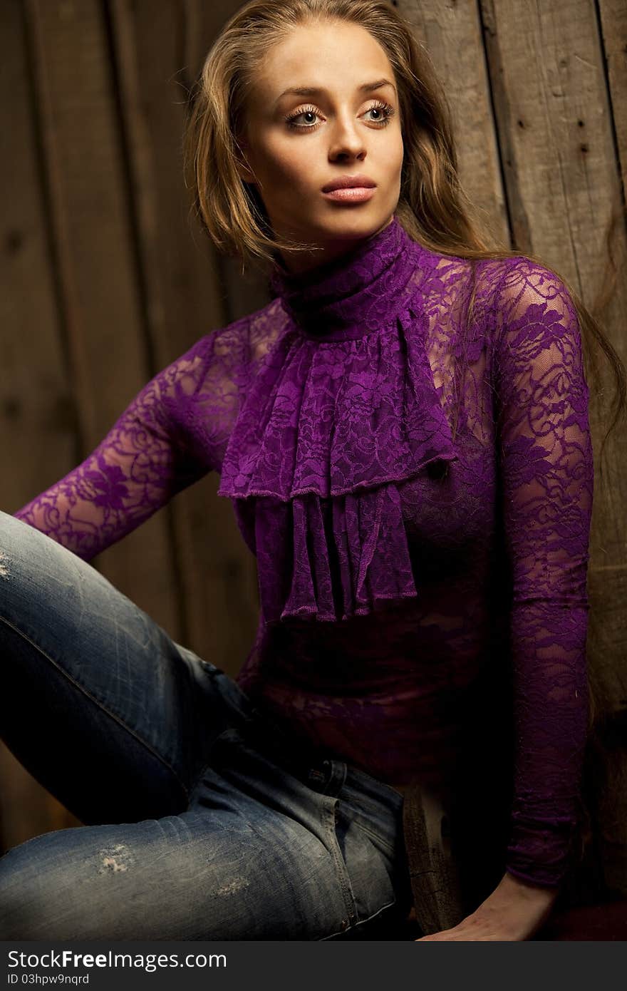 Fashion photo of young sensual woman in blue jeans and kombidress against wooden background