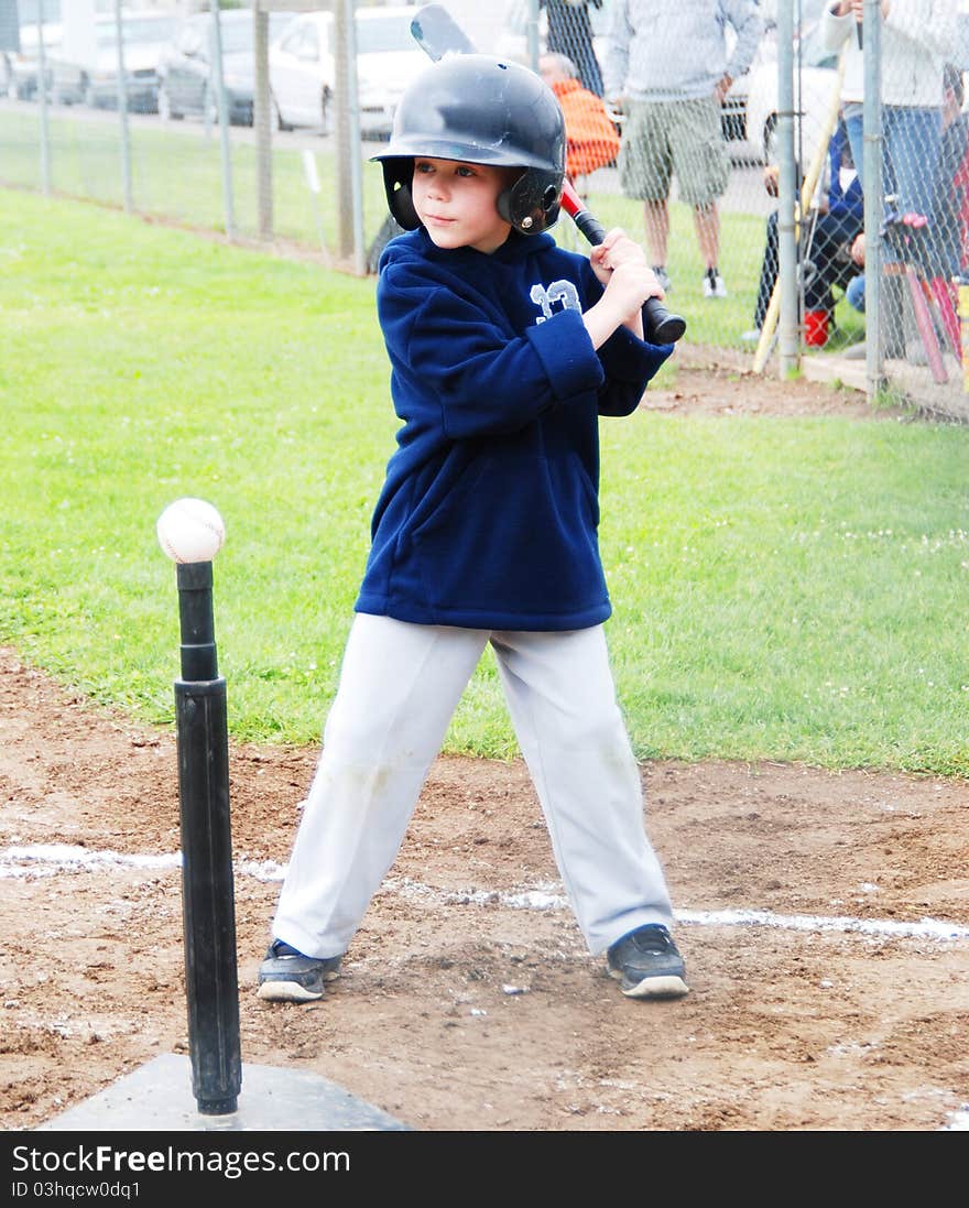 A T-Ball player at bat in a game in Salem, Oregon wearing a blue jacket, gray pants and black helmet. A T-Ball player at bat in a game in Salem, Oregon wearing a blue jacket, gray pants and black helmet.