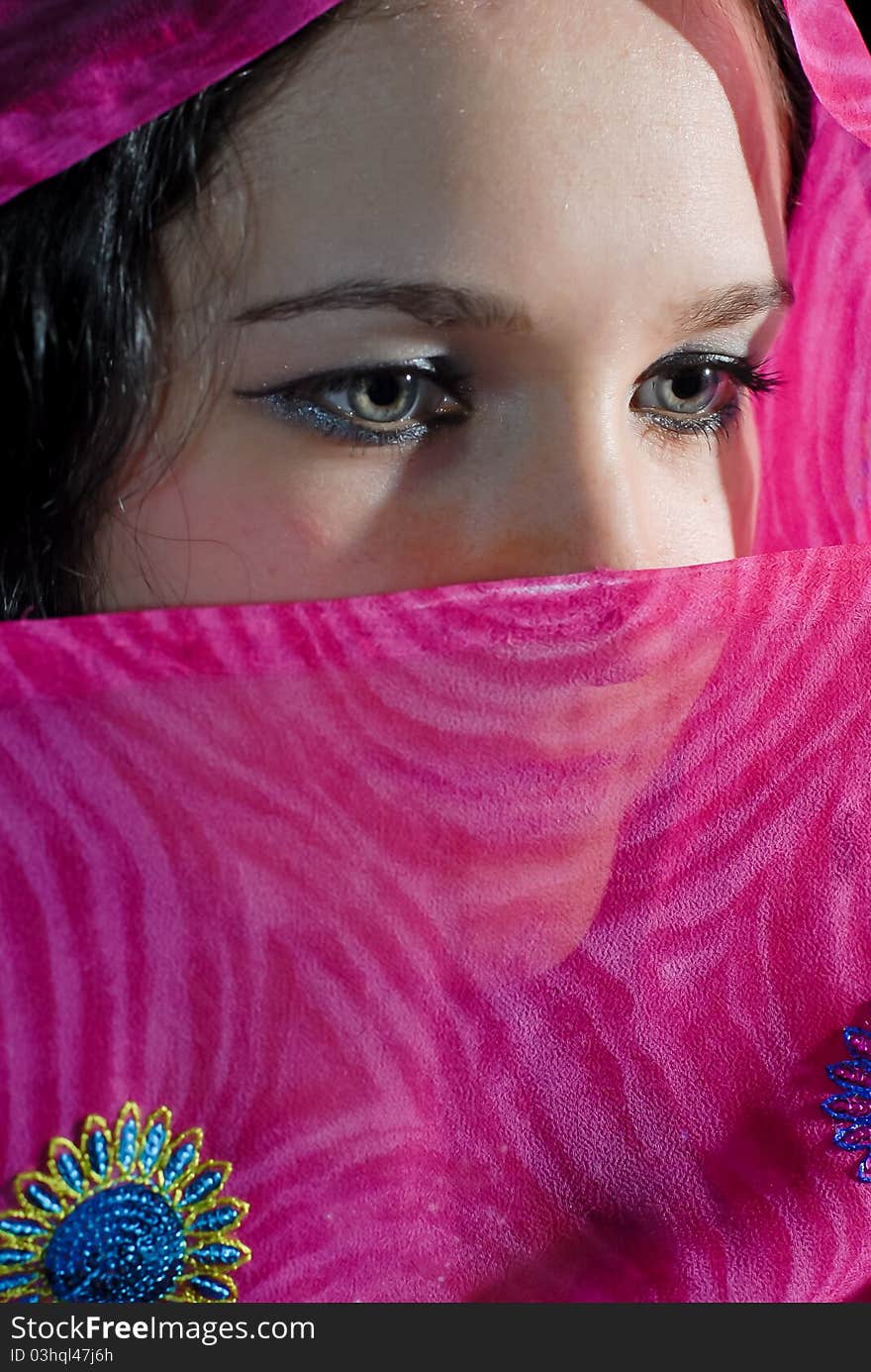 Young woman hiding part of her face under pink shawl. Young woman hiding part of her face under pink shawl