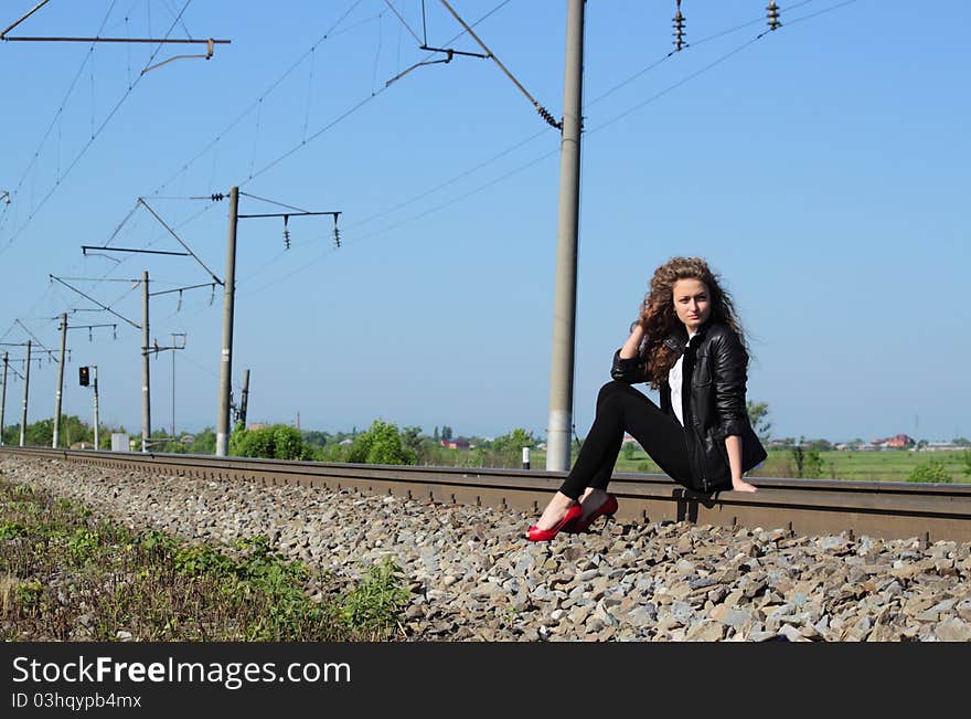 A girl sits on the rail waiting for the train. A girl sits on the rail waiting for the train