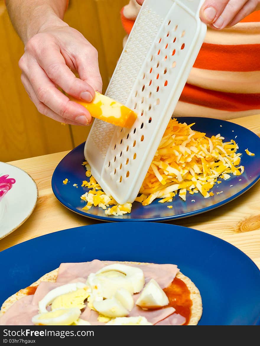 Closeup hands making pizza at kitchen. Shredding cheese. Closeup hands making pizza at kitchen. Shredding cheese.