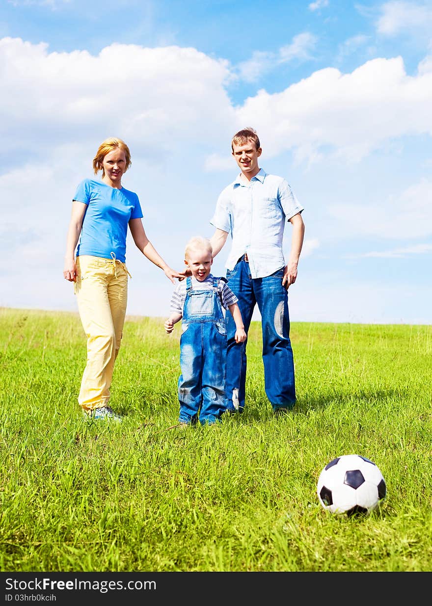 Happy young family playing football outdoor on a summer day