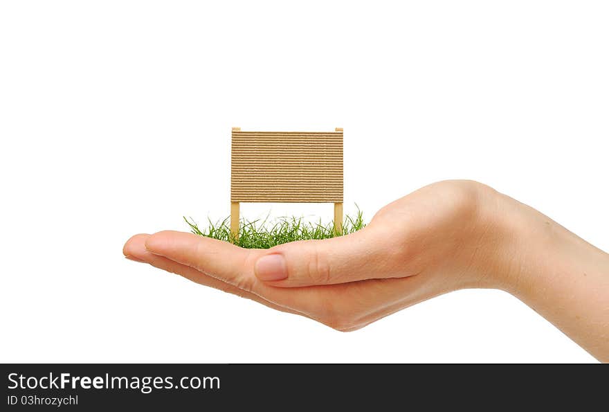 Cardboard sign with green grass on human hand on white