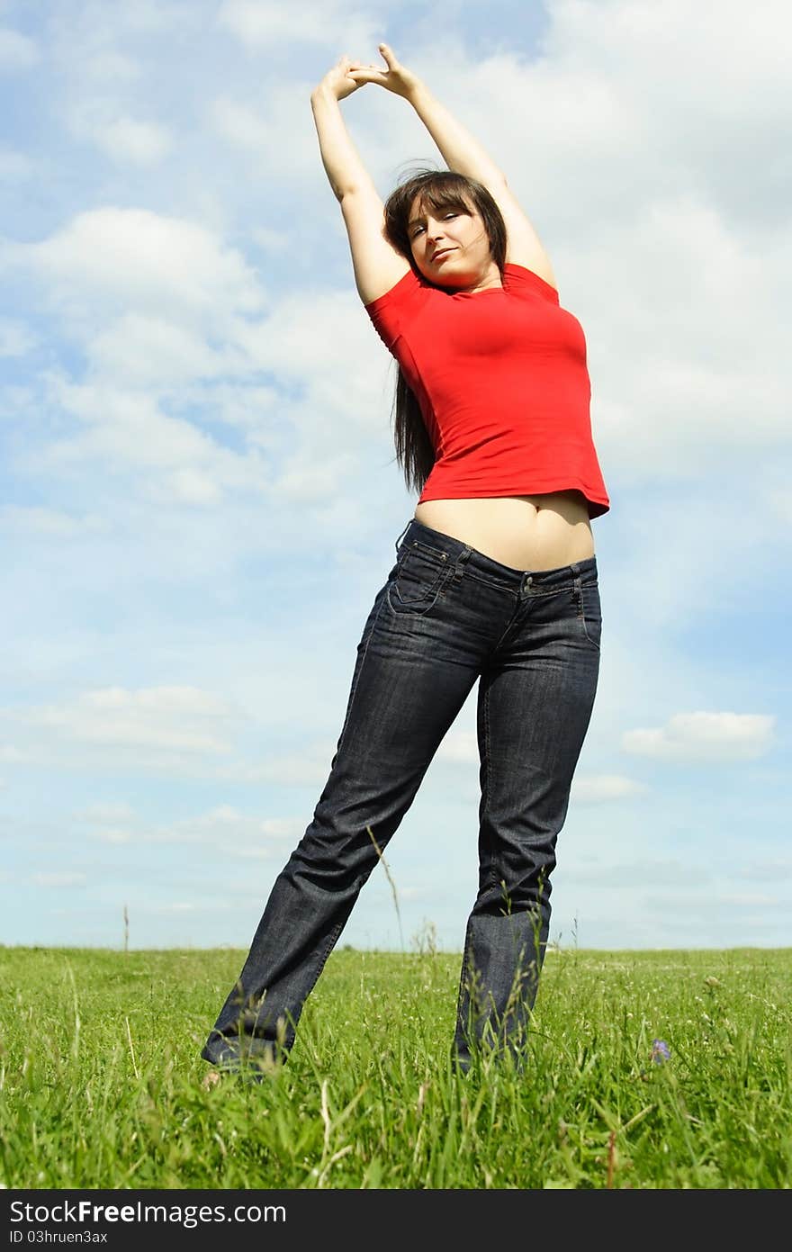 Young girl standing on summer meadow, hands up