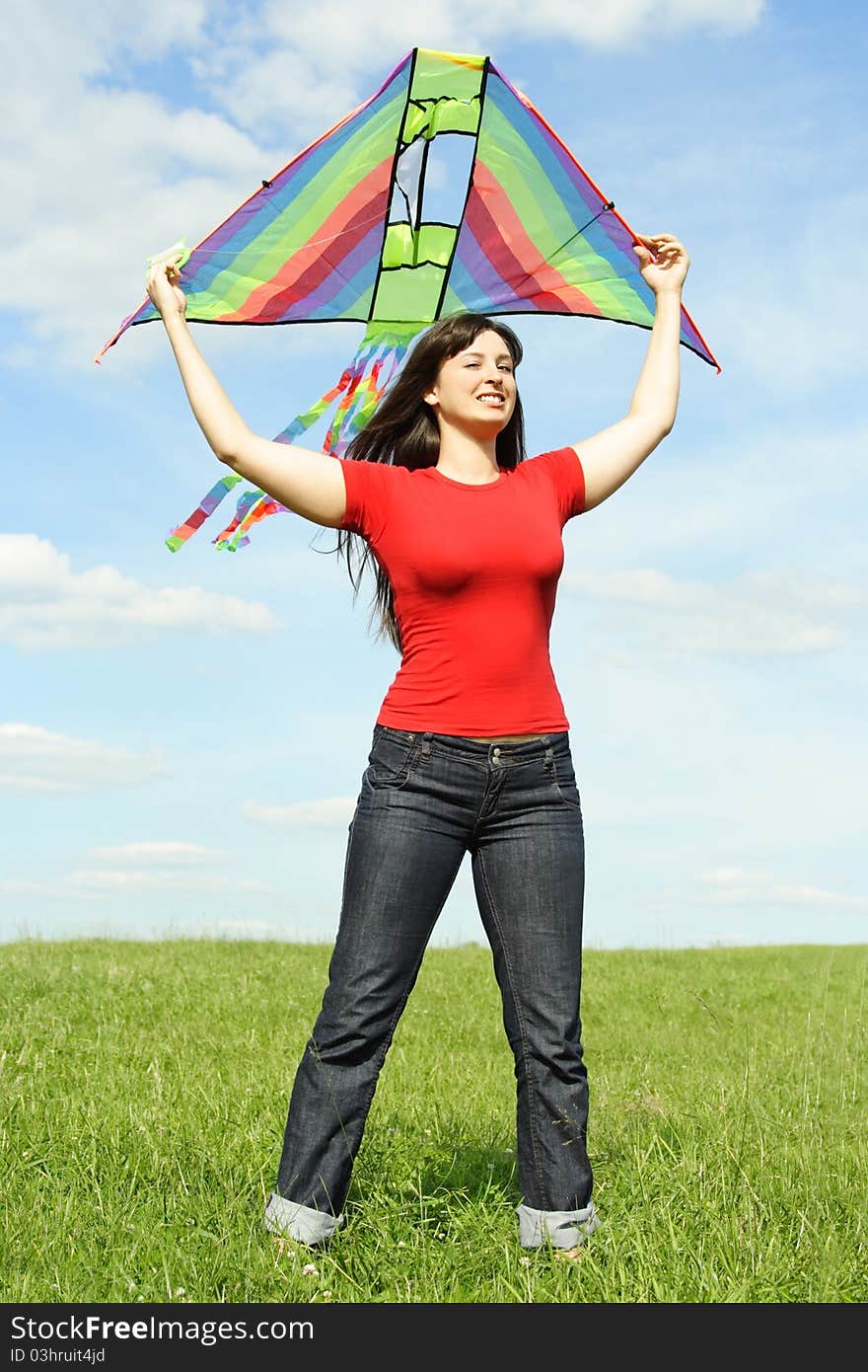 Young girl in red shirt standing on summer meadow and holding kite above head. Young girl in red shirt standing on summer meadow and holding kite above head