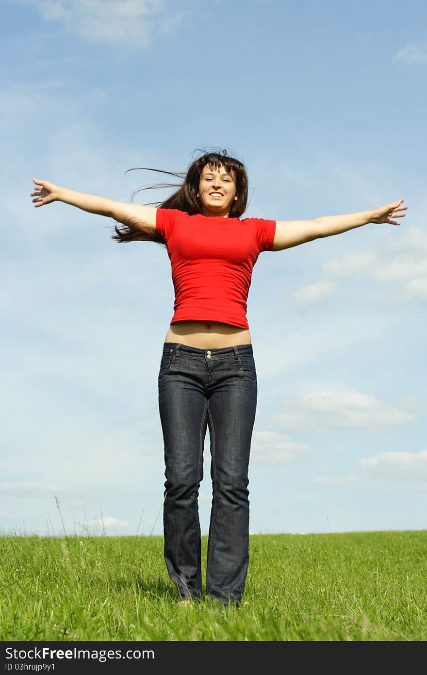 Young girl in red shirt standing on summer meadow, hands apart, blue sky. Young girl in red shirt standing on summer meadow, hands apart, blue sky