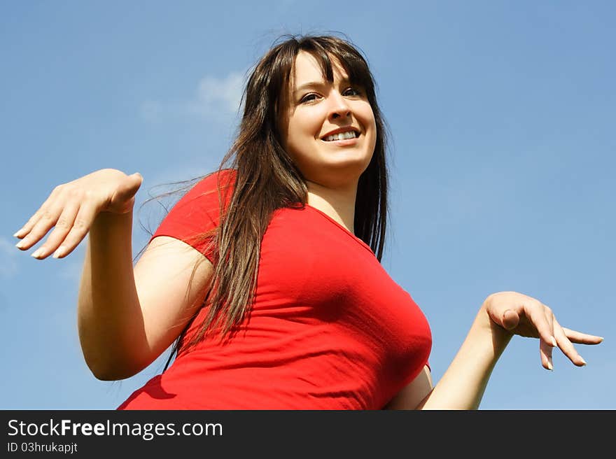 Girl in red shirt making gesture, blue sky