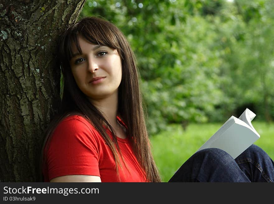 Girl siting near tree and reading book