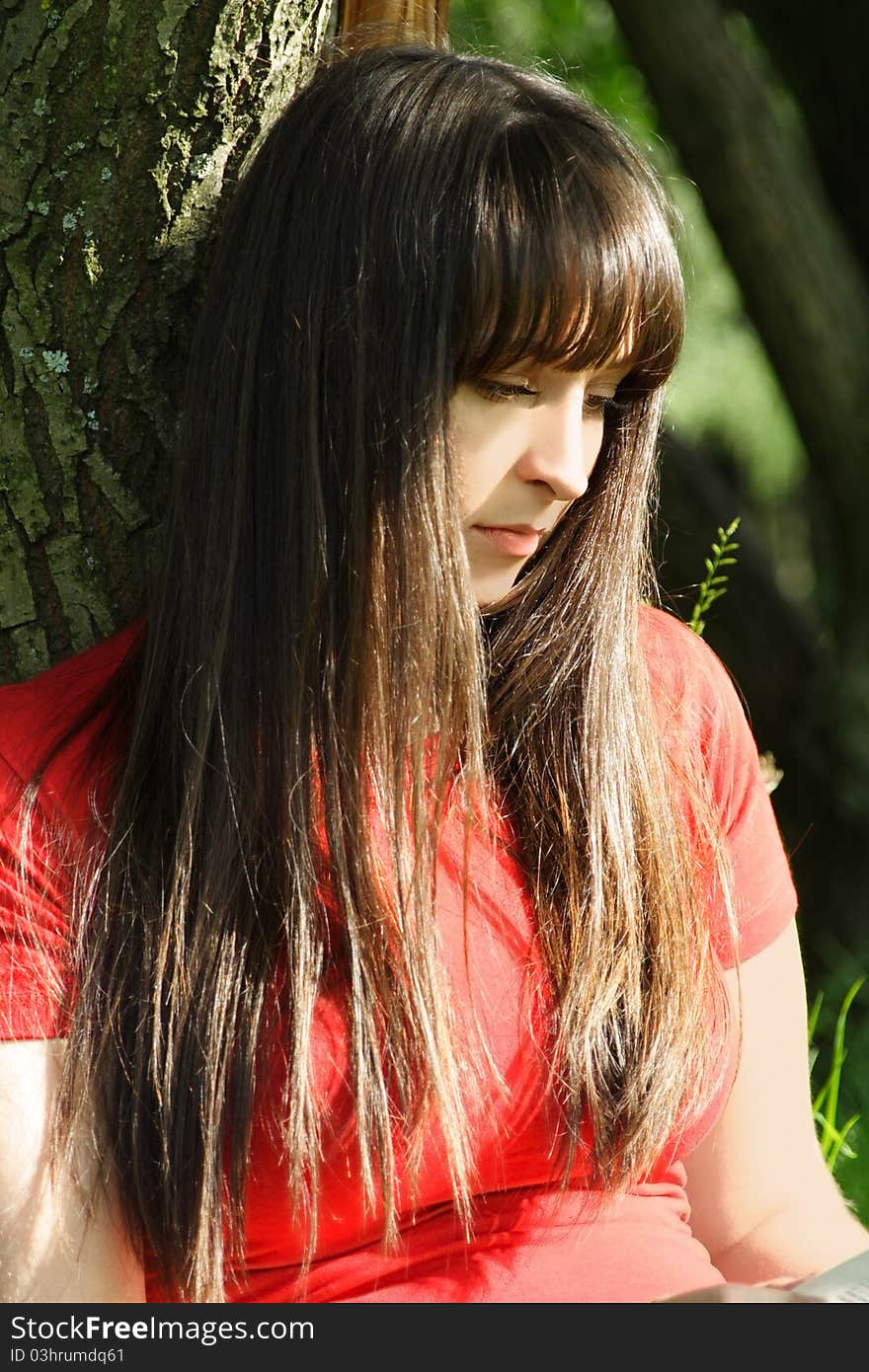 Girl in red shirt siting near tree