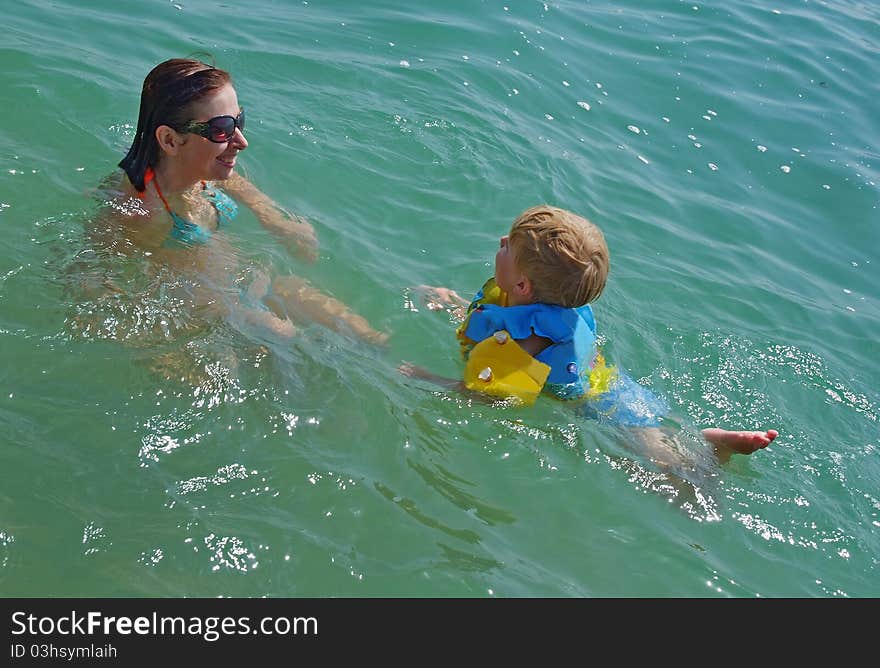 Happy family of mother with kid in the ocean waves. Happy family of mother with kid in the ocean waves