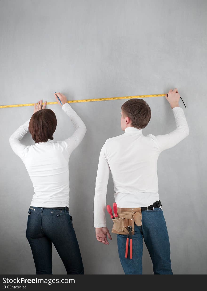 Couple measuring wall for home redecorating