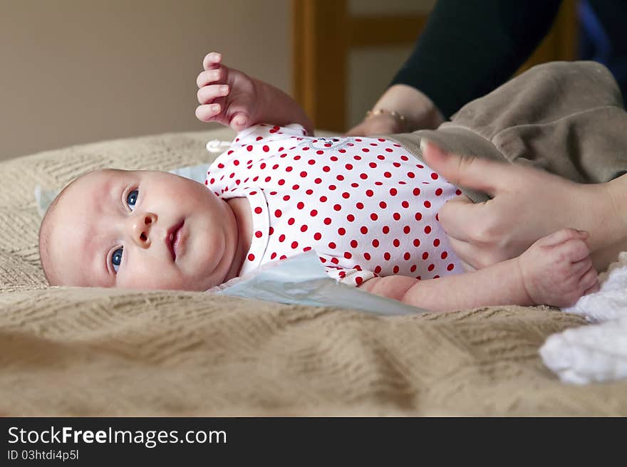 Female hands putting pants on her little lying baby. Female hands putting pants on her little lying baby