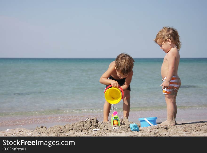 Two children playing with sand on beach. Two children playing with sand on beach